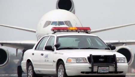 Police car on a runway in front of a plane